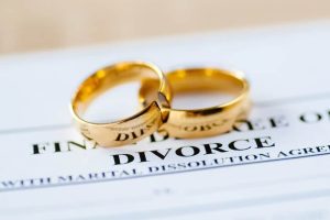 Two gold wedding rings resting on a divorce dissolution agreement document, symbolizing marriage dissolution.