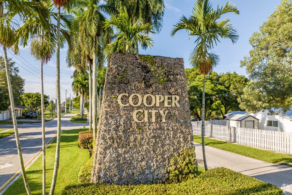 cooper-city-fl Sunny coastal city with high-rise buildings along a marina and palm trees, blue sea in the background